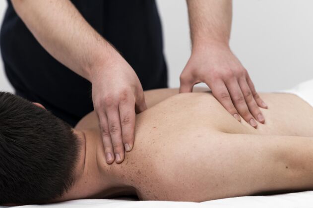 运动理疗师给男病人做背部按摩愈合治疗理疗师