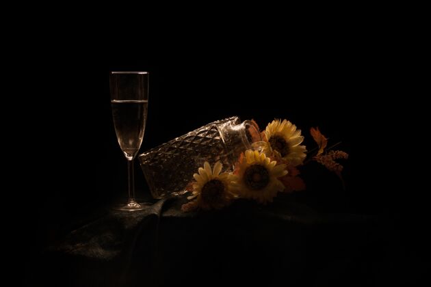 黑桌子上放着向日葵和香槟的罐子 背景是黑色的向日葵酒精开花
