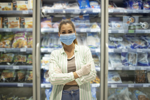 食品杂货店超市里戴着防护面具和手套的女人站在杂货店的食物旁的画像Covid19购物口罩