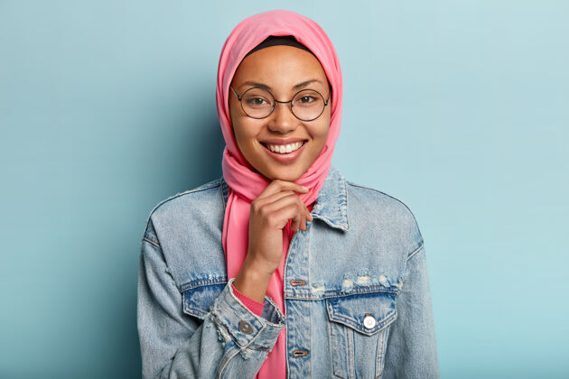 现代美丽的阿拉伯女人带着牙齿微笑的头像 托着下巴 戴着圆眼镜 穿着特别的传统服装伊斯兰阿拉伯文化