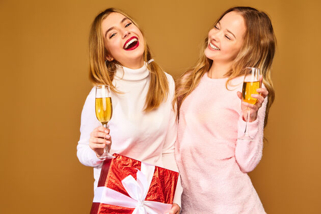 金发带着大礼盒的模特戴着酒杯喝香槟庆祝新年微笑女朋友新年