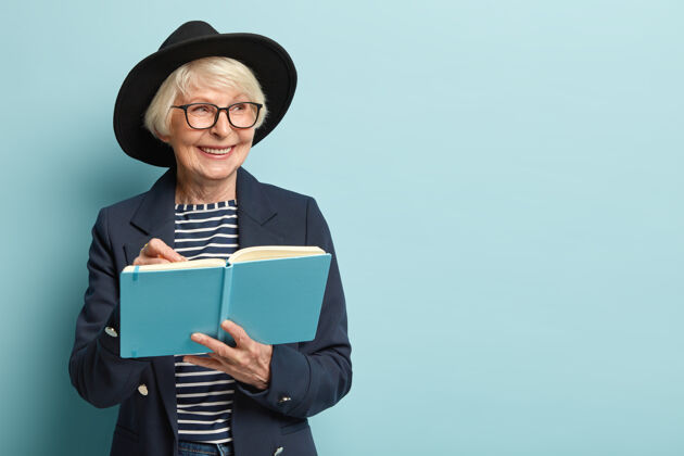 休闲人 年龄 自由时间的概念很高兴老年女性在她的蓝色记事本上写下清单眼镜工作皱纹