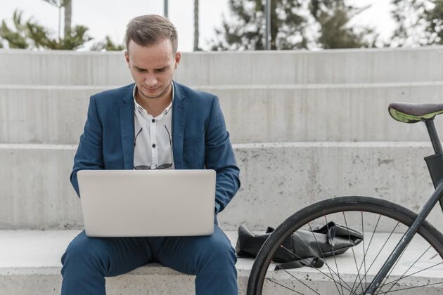 骑自行车的前视图：一个男人在自行车旁边的笔记本电脑上工作户外骑自行车运动