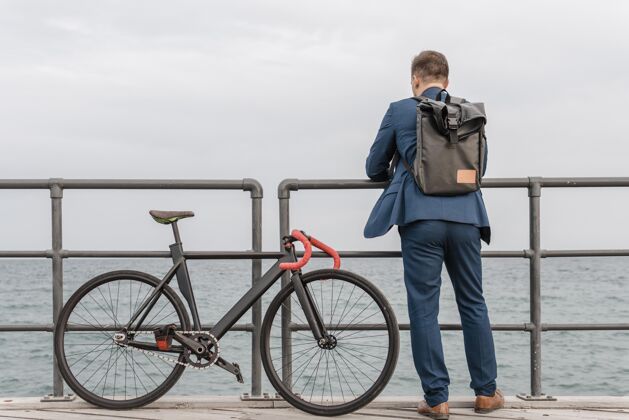 生态背着背包的男人站在他的自行车旁边骑自行车的健康运动的