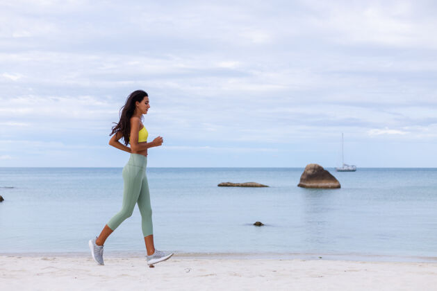 健康海滩上穿着五颜六色运动服的迷人年轻女子人人锻炼