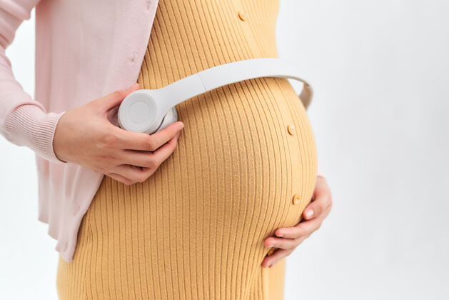 父母孕妇肚子上戴着耳机女人期待亚洲人