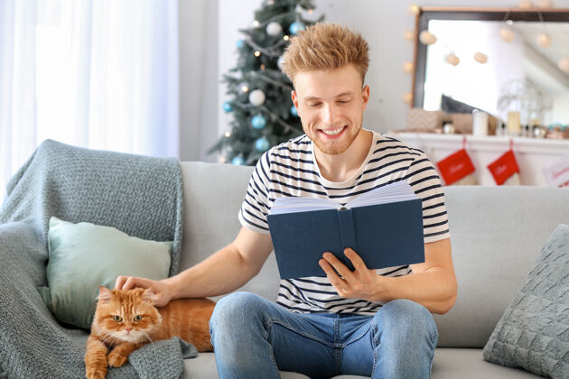 品种圣诞夜 一个带着可爱猫在家看书的年轻人波斯可爱人