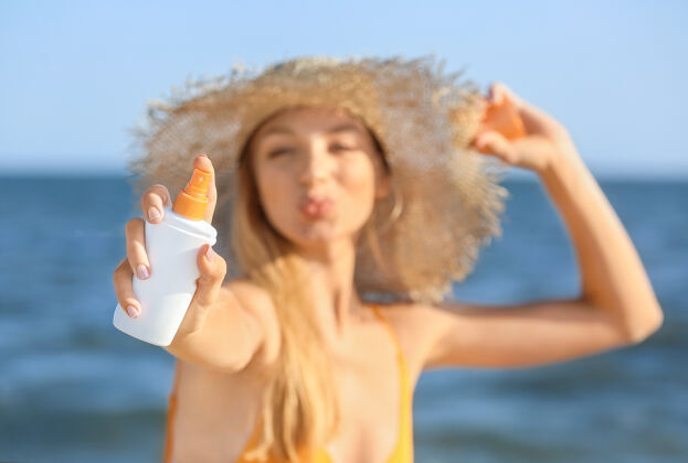 日光浴美丽的年轻女子在海边涂防晒霜女人度假胜地套装
