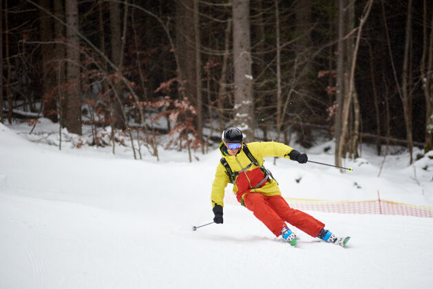 木材年轻男性滑雪者下山滑雪和在树木繁茂的山坡上做雕刻转弯的单一下降下雪时滑雪度假行动骑行