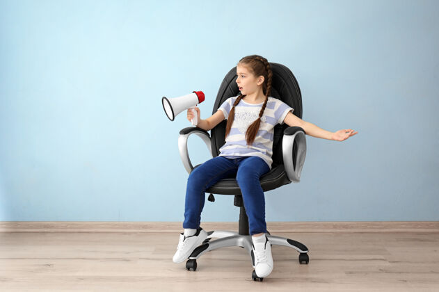 领导小女孩拿着扩音器坐在空房间的椅子上扩音器声音墙