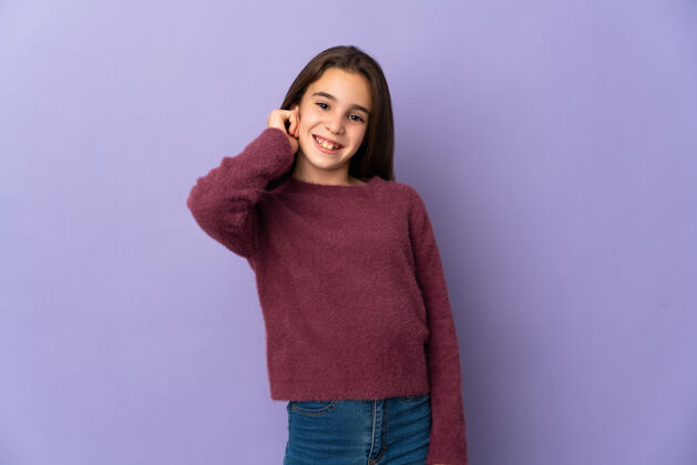 骄傲被隔离在紫色墙上的小女孩笑了快乐手臂模特