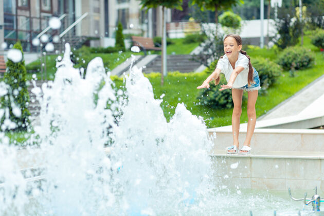 积极无忧无虑的童年可爱快乐的女孩微笑着向水伸出双手公寓玩耍水