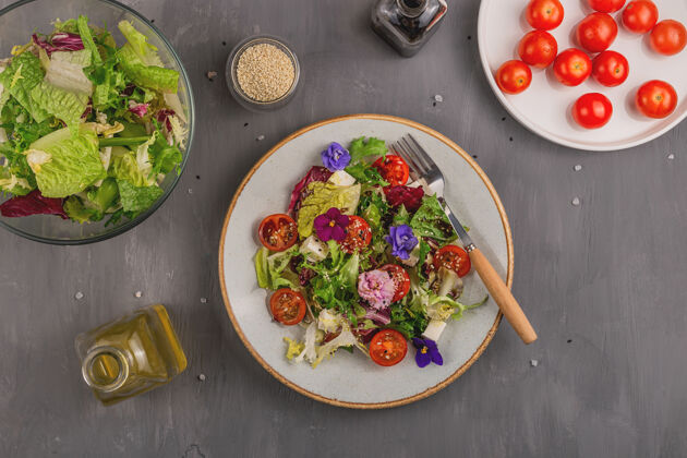食用花一张灰色的桌子上有西红柿 莴苣和奶酪的素食沙拉 上面点缀着可食用的花和配料春季食品概念有机乡村饮食