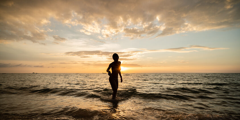 年轻在多云的天空和日落的海滩上 女人的身影自然水户外