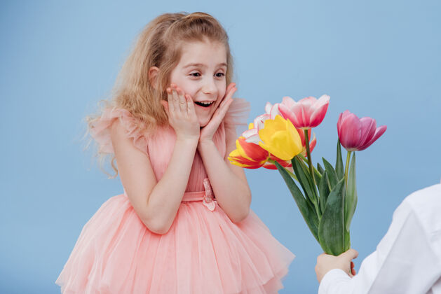 衣服小女孩收到鲜花 隔离在蓝色的墙上 特写 两个小孩花束裙子提供