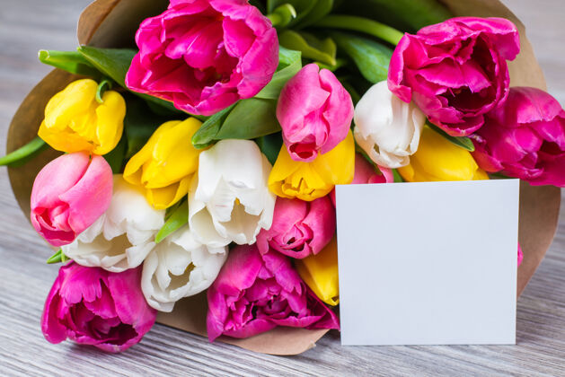 温柔你好 春天的概念一束美丽的粉红色 黄色 白色花的特写照片 用纸包着 明信片躺在灰色的木桌上花空留言