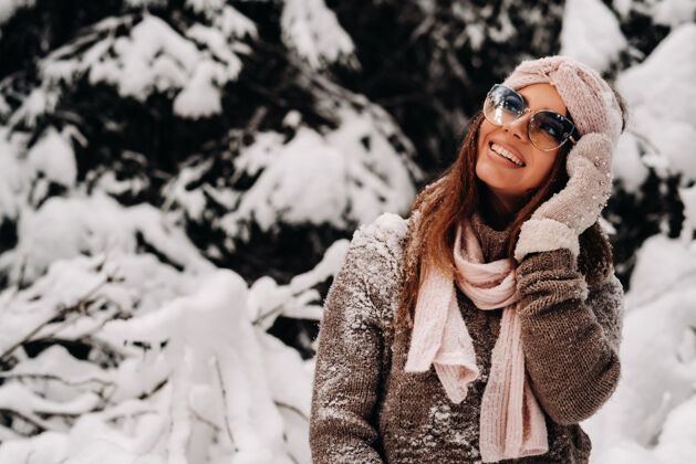 年轻冬天 一个穿着毛衣戴着眼镜的女孩在白雪覆盖的森林里模特头发成人
