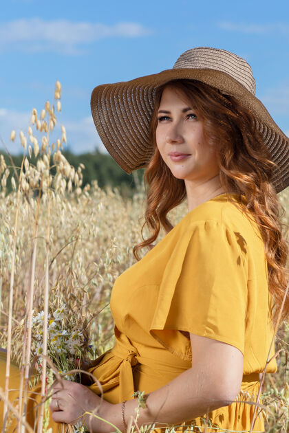 农村在一个阳光明媚的夏日 一位年轻漂亮的孕妇穿着黄色的裙子 戴着黄色的帽子 走过一片麦田黄色可爱肚子