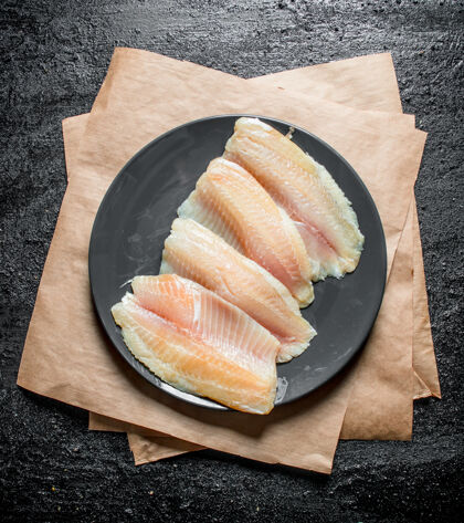 海在黑色的乡村桌子上用纸把鱼片放在盘子里部分鱼美食