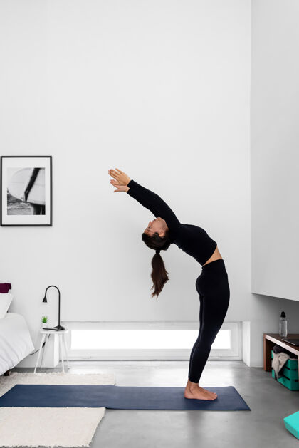 训练年轻苗条的女人在家里的现代简约卧室练习瑜伽瑜伽运动普拉提
