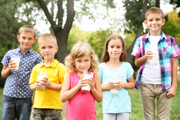 乳制品公园里戴着牛奶杯的可爱的孩子们牛奶公园户外