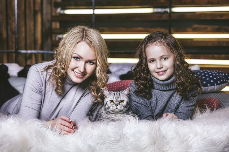 孩子时尚可爱的小女孩和美女抱着一只英国小猫在一起很开心宠物圣诞节拥抱