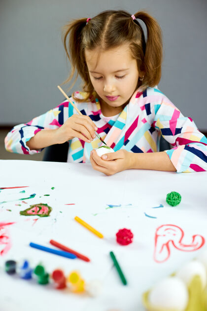 快乐快乐的小女孩在家画画 用毛笔蛋画画孩子准备复活节 玩得开心 庆祝节日复活节快乐 diy工艺绘画乐趣