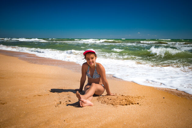 白天在一个阳光明媚的夏日里 快乐美丽的小女孩在沙滩上休息 在沙滩上玩耍风暴早晨刮风