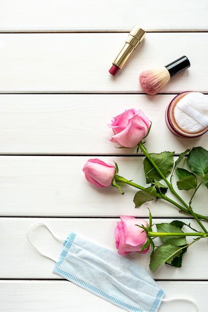 唇膏白色木质背景上的化妆 玫瑰 医疗面罩和复印空间的顶视图布置covid-19时代的美的概念粉刷化妆品病毒防护