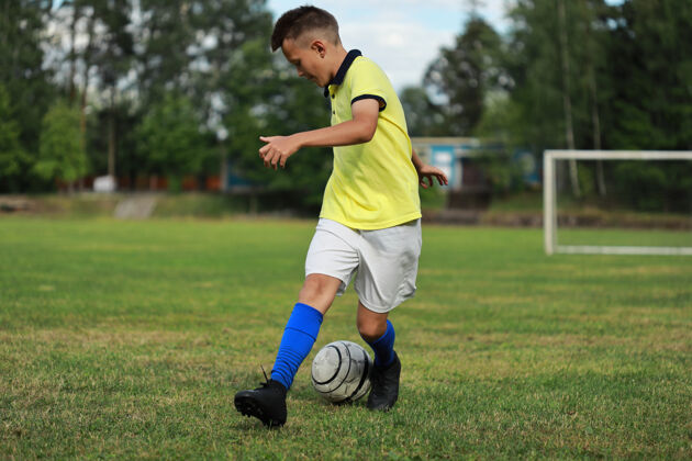 游戏穿黄色t恤的男孩足球运动员在足球场上玩球足球游戏比赛