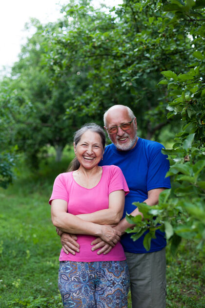 公园夏日苹果园里可爱的老男人和老女人的画像60岁50岁老年