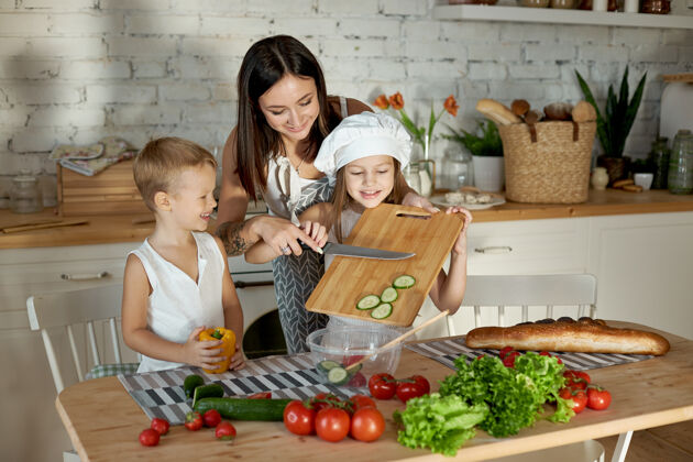 食物妈妈和孩子们一起做午饭一个女人从儿子那里教女儿做饭素食主义和健康的天然食物新鲜妈妈营养