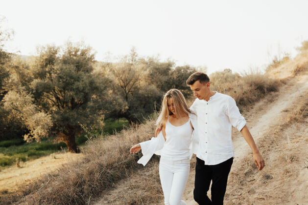 户外一对穿着白色衣服的情侣在夏日公园散步 拥抱 面带微笑举行一起乡村