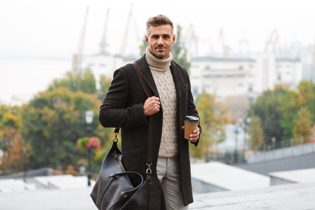 杯子照片中 30多岁的白种人穿着夹克 手里拿着外卖咖啡 走在城市街道上站立城市帅气