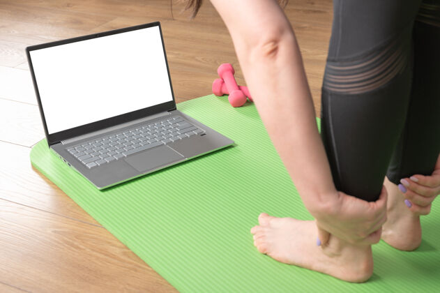 练习用笔记本电脑在瑜伽垫上特写女性的脚和手掌人们在网上练习瑜伽数字设备视频培训课程的概念运动健活方式视频