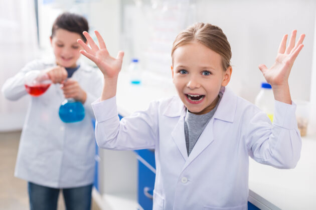 化学做什么积极的情绪可爱的女孩看着你 举起她的手 而不知道该做什么学生生物技术科学家