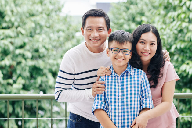 父母快乐的亚洲母亲 父亲和他们的孩子站在公寓阳台上微笑的画像欢呼拥抱成人