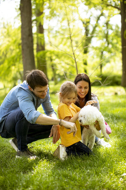 妈妈美丽幸福的一家人在公园里和比雄狗在户外玩得很开心孩子乐趣小