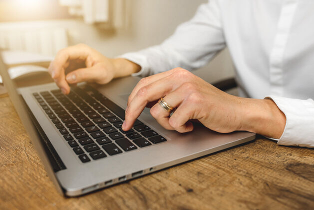 键盘白种人在办公室木桌上用笔记本电脑手工打字的特写镜头打邮件网上购物网上银行在电脑上打字桌子使用工作
