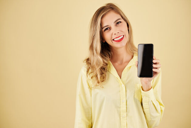 白种人开朗金发女人展示新款智能手机的工作室肖像女性女孩使用电话