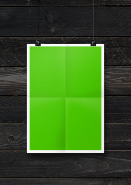 活页夹绿色折叠海报挂在一个黑色的木墙上与剪辑空白模型模板悬挂投资组合房间