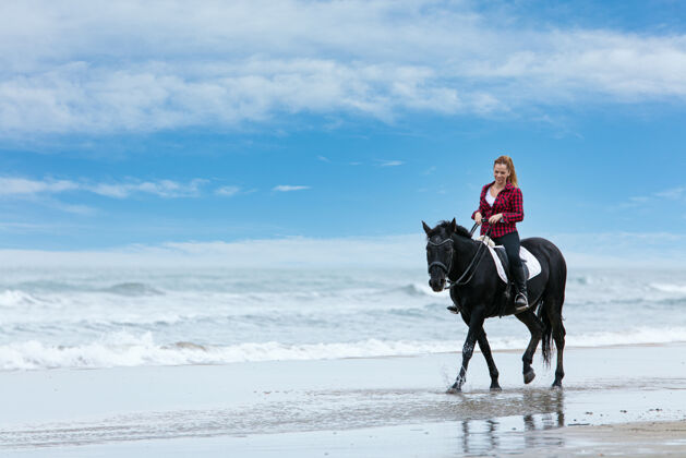 天空阴天海滩上骑马的年轻女子人运动波浪