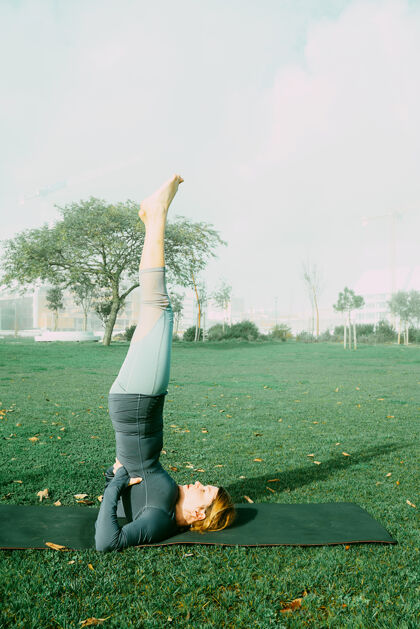 女人在公园里用瑜伽垫做瑜伽 伸展运动 锻炼的年轻女子天生的瑜伽初学者姿势医疗理念训练户外健康