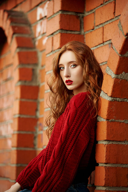 户外穿着红毛衣的红发女青年在公园里散步晚霞下一位时尚红发女子的秋美写真休闲女孩红发