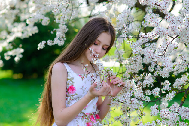 欢呼美丽的春天 美丽的小女孩在盛开的苹果园里白天孩子公园