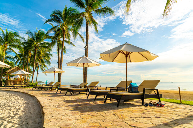 游泳池美丽的豪华伞和椅子周围的室外游泳池在酒店和度假村日落椰子床