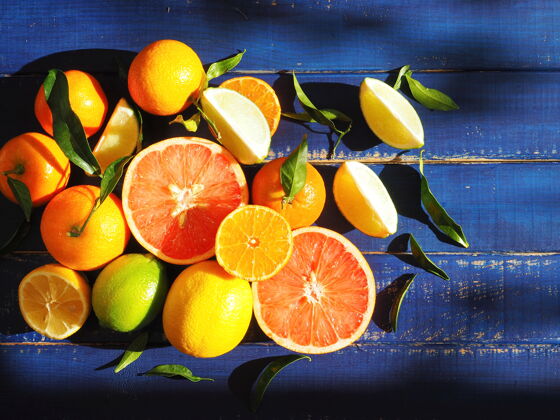 切有叶子的柑橘类水果在蓝色的木头表面热带叶新鲜