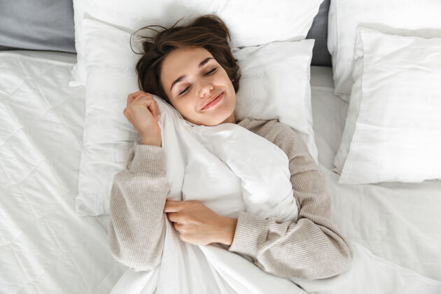 舒适一个微笑的年轻女孩在床上放松的俯视图肖像吸引力卧室