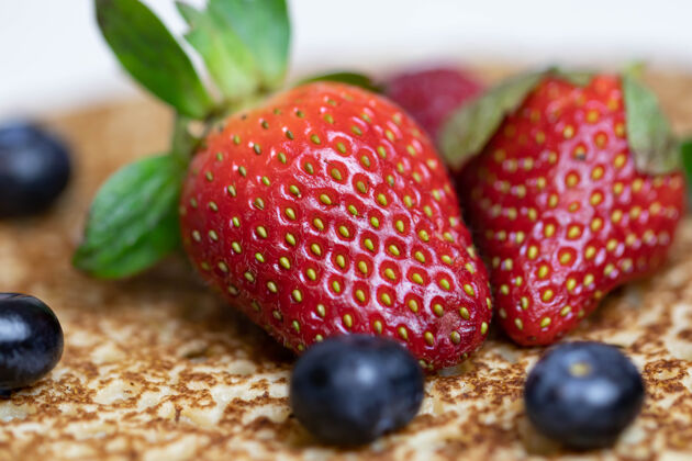 浆果成熟多汁的草莓和蓝莓躺在美味的煎饼上俄罗斯料理国家菜 带新鲜浆果烹饪薄饼传统