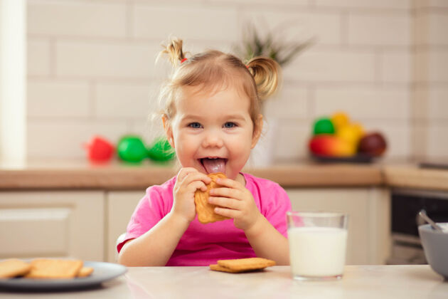 美味快乐的宝宝坐在厨房的餐桌旁 胃口大开脸人牛奶